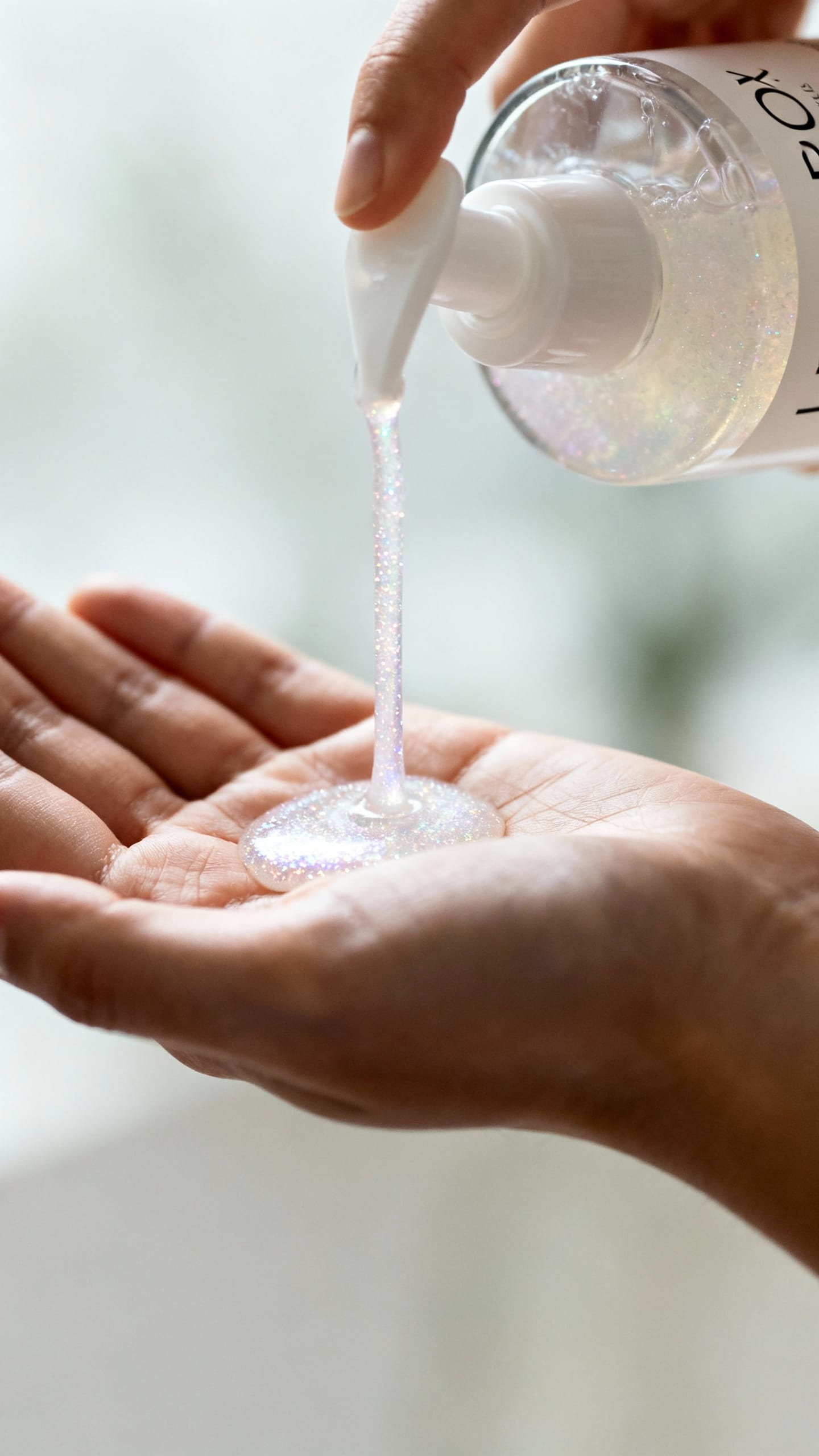 Closeup of Olaplex No.4 bottle dispensing pearly shampoo onto palm